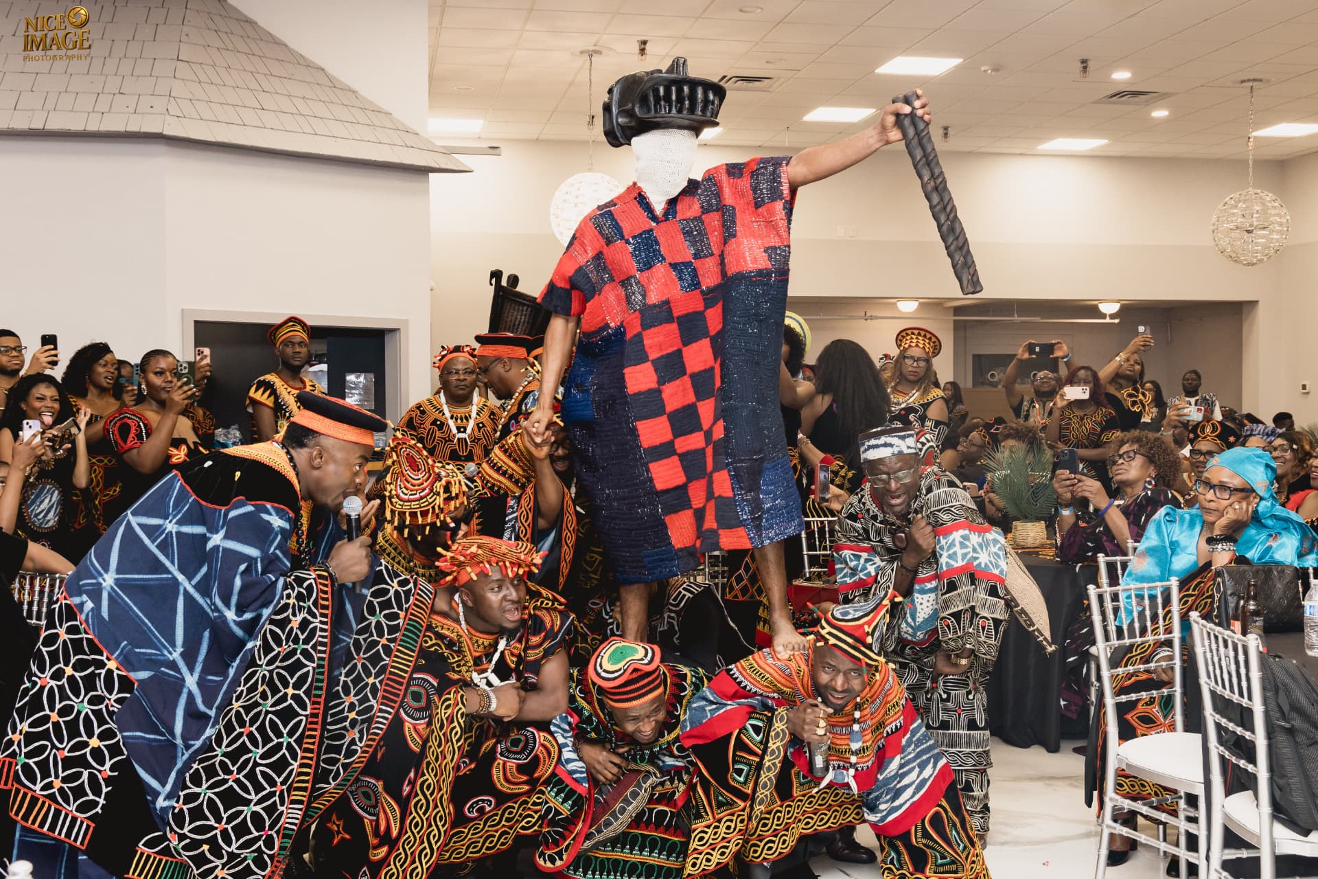 A masked ceremonial figure in patterned regalia is lifted overhead by celebrants at a BotangRecords cultural event, phone cameras raised throughout the crowd.